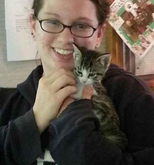 A woman holding a kitten in her arms.
