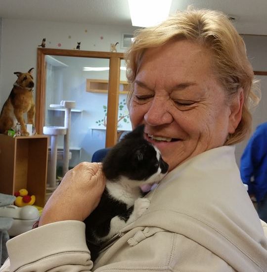 A woman holding a black and white kitten in her arms.