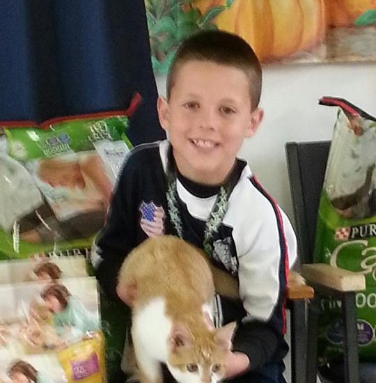 A kid holding a cat and smiling