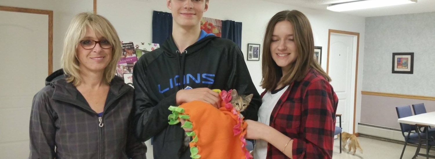 A family of three holding a cat in the room