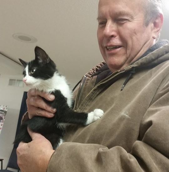 A man holding a black and white cat.