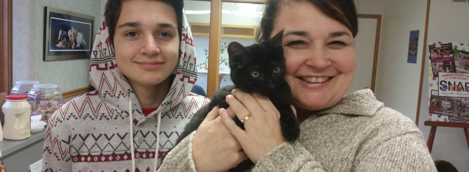 A woman and a boy with a black kitten