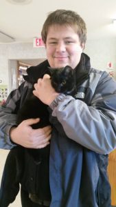 A young man holding a black cat.