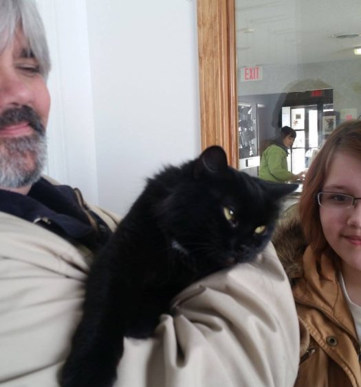 A man holding a black cat.