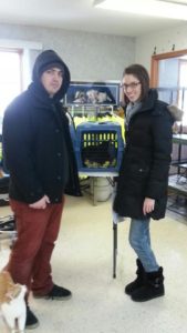 Two people standing in front of a cat crate.