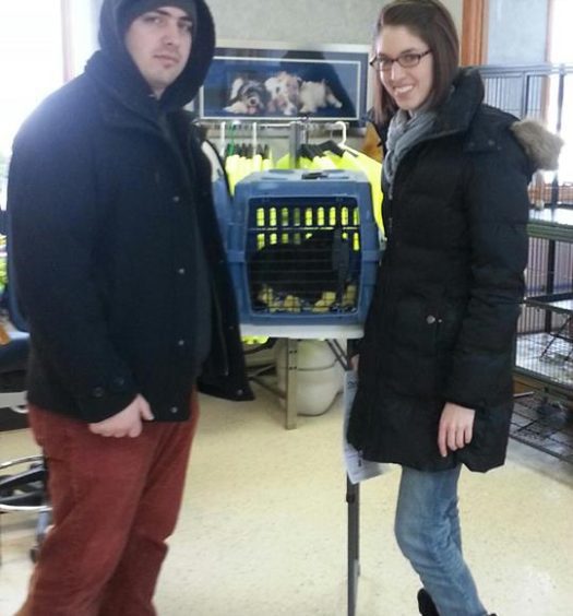Two people standing in front of a cat crate.