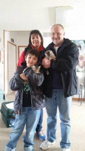 A family holding two kittens in a living room.