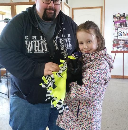 A man and a girl holding a black cat.