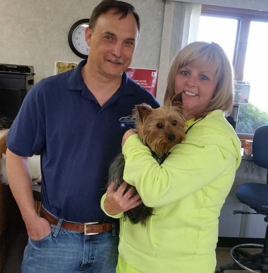 A man and woman holding a dog in an office.