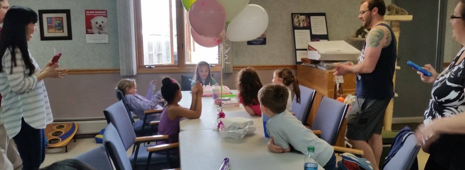 A bunch of kids sitting on a table with balloons