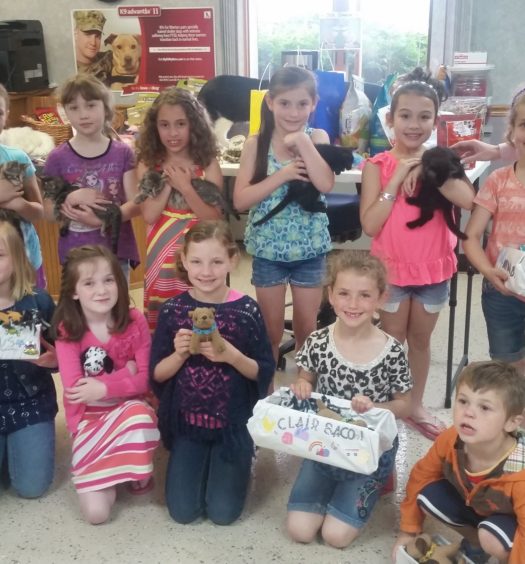 A bunch of kids holding cats and toys