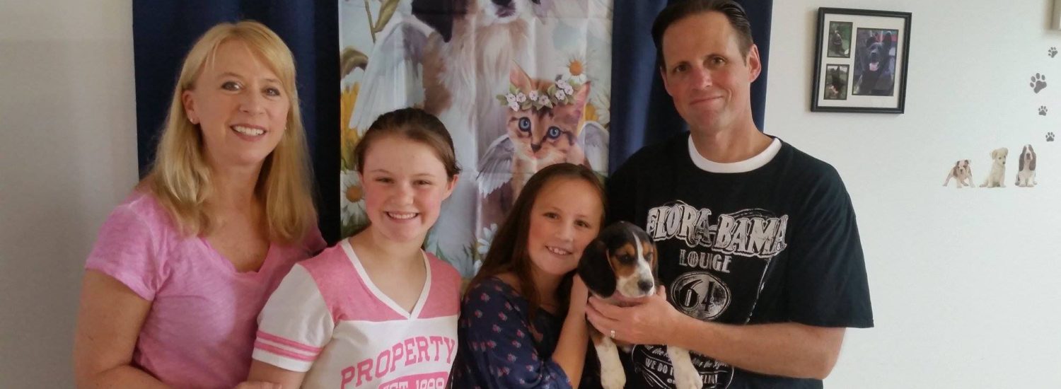 A family posing for a picture with a puppy.