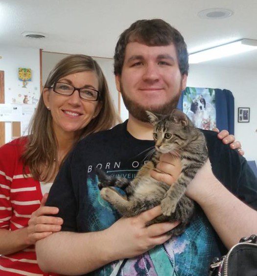 A man and woman holding a cat in an office.