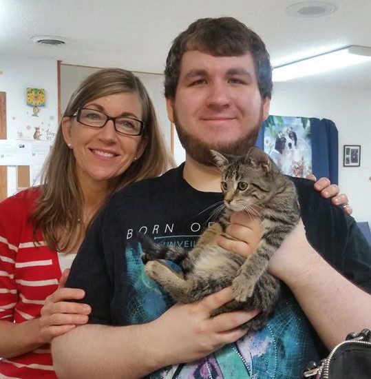 A man and woman holding a cat in an office.