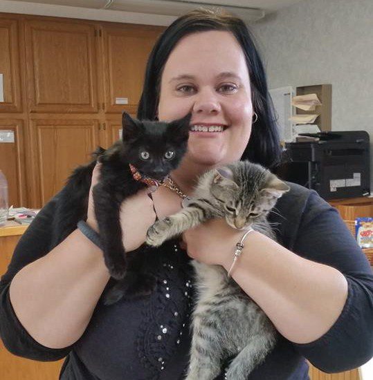 A woman holding two kittens in front of an office.