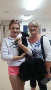 A girl and a woman holding a dog in a room