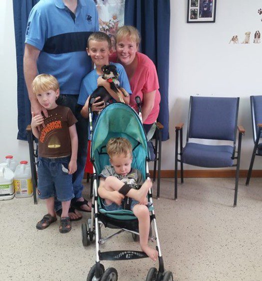 A family posing in a waiting room with a baby in a stroller.