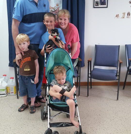 A family posing in a waiting room with a baby in a stroller.