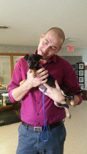 A man holding a small black and tan dog.