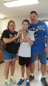 A man and woman are posing for a picture with a cat.