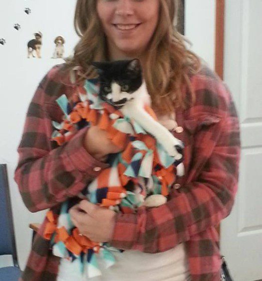 A woman holding a black and white cat.