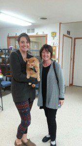 Two woman holding a cat in a room