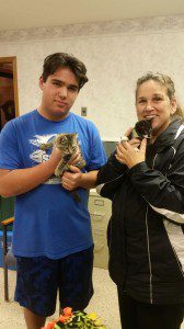 A man and woman holding kittens in a room.