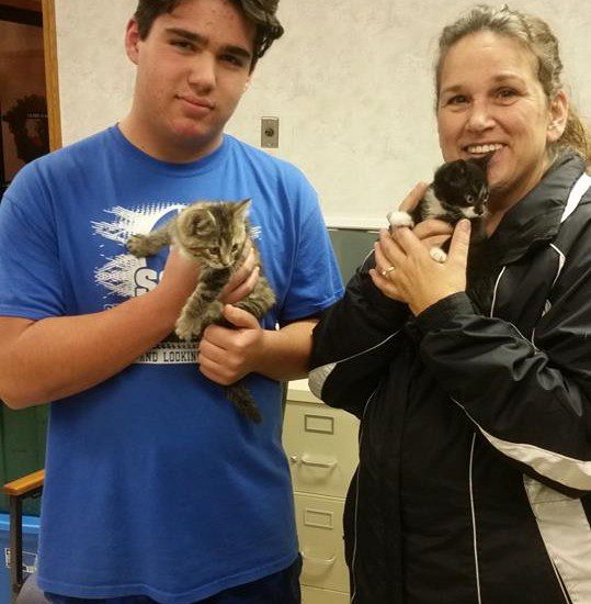 A man and woman holding kittens in a room.