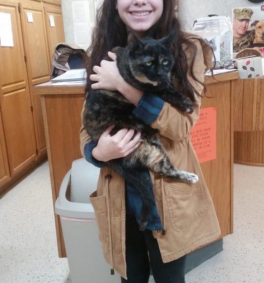 A young woman holding a cat in an office.