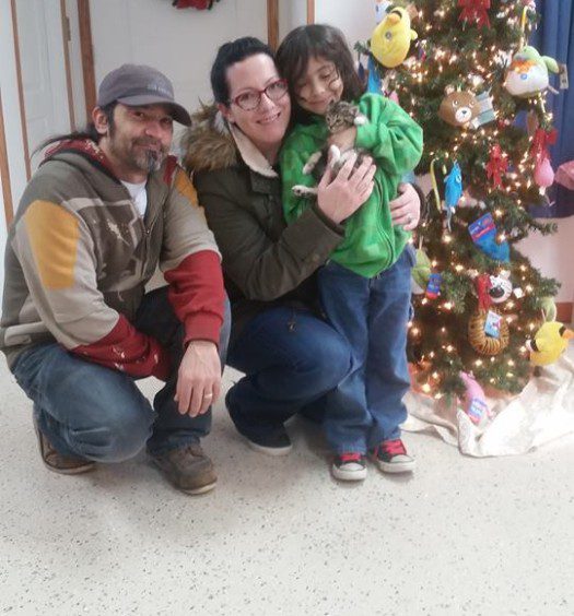 Three people posing for a photo in front of a christmas tree.