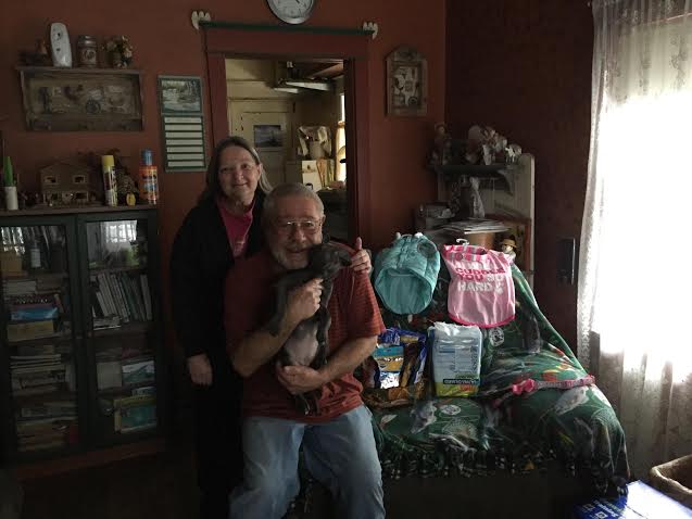 A man and woman posing in a room with a lot of items.