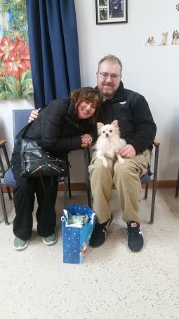 A man and woman sitting in a waiting room with a dog.