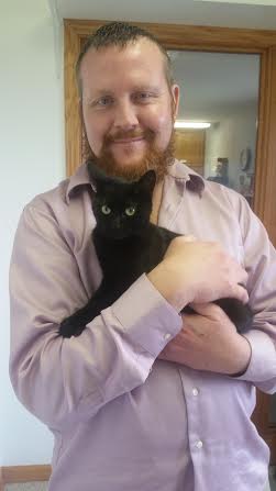 A man holding a black cat on his hands