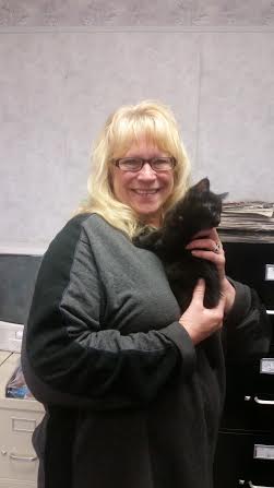 A woman holding a black cat in an office.