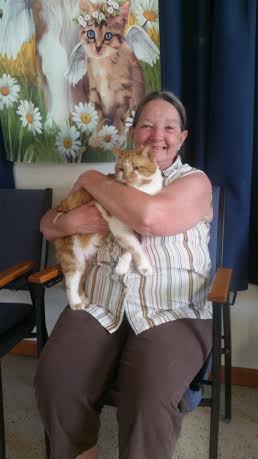 A woman sitting in a chair holding a cat.
