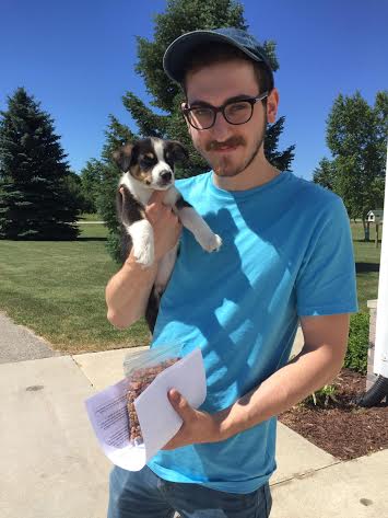 A man holding a puppy and a piece of paper.