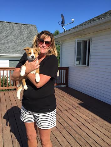 A woman holding a puppy on a deck.