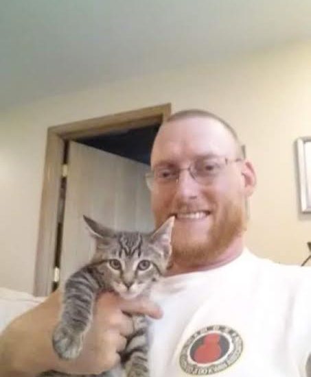 A man holding a kitten in his arms.