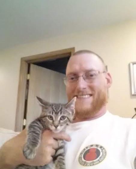 A man holding a kitten in his arms.