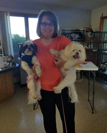 A woman holding two small dogs in a room.