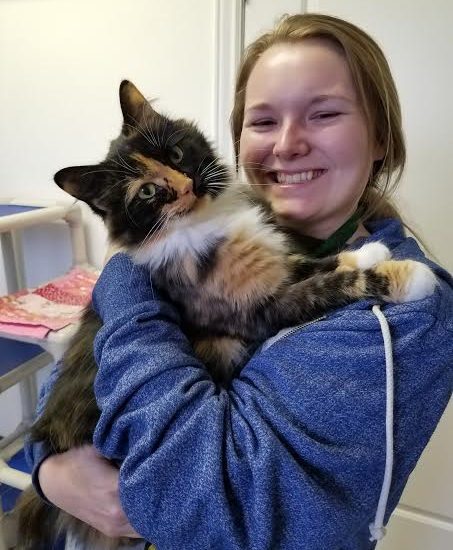 A girl holding a cat and smiling
