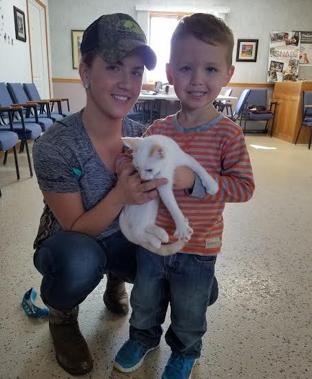 A woman and a young boy holding a white kitten.