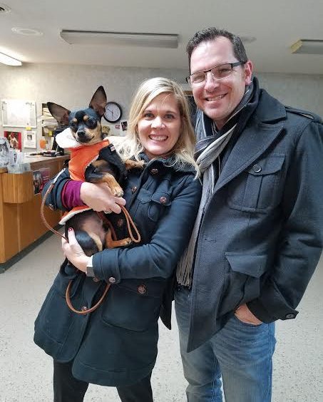 A man and woman posing with a dog in a hospital.