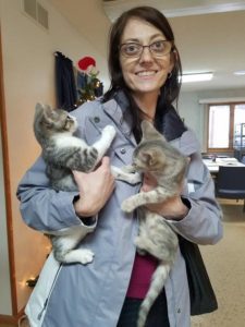 A woman holding two kittens in her arms.