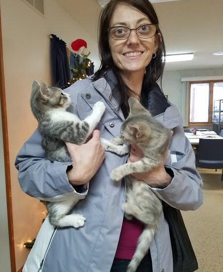 A woman holding two kittens in her arms.