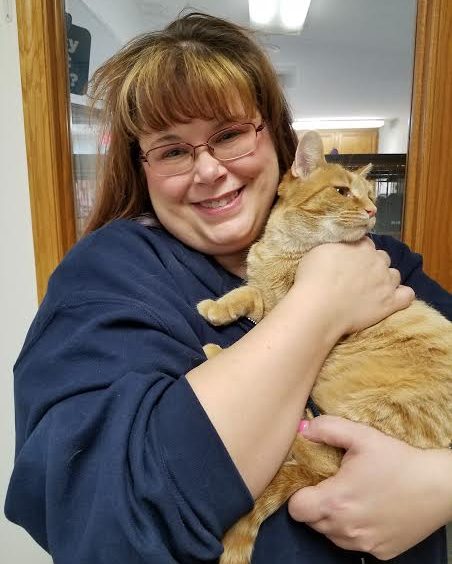 A woman holding an orange cat in her arms.