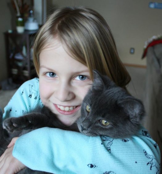 A small girl holding a black cat