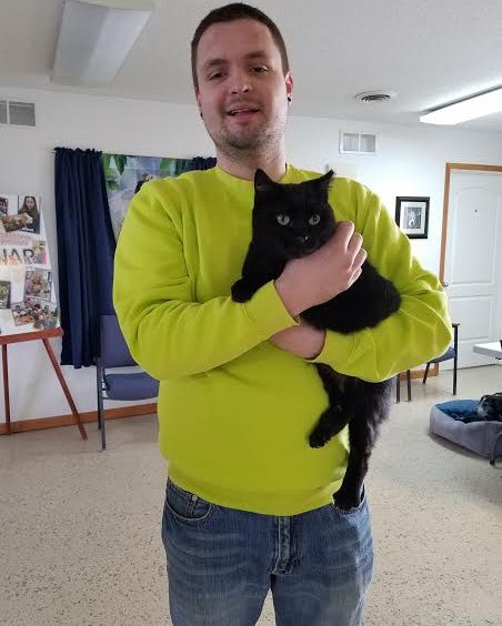 A man holding a black cat in a room.