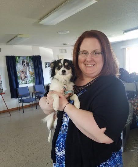 A woman holding a black and white dog in a room.