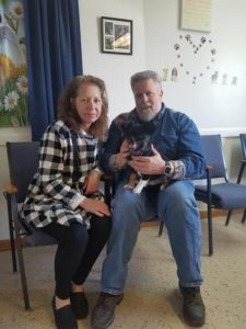 A man and woman sitting in a room with a dog.